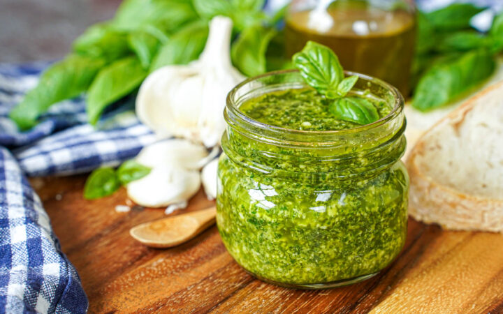 Pistou (Provençal Basil Sauce) in a jar next to bread slices and garlic cloves.