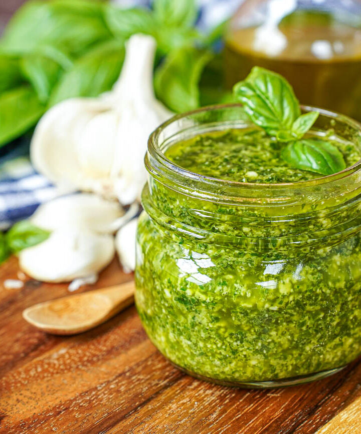 Pistou (Provençal Basil Sauce) in a jar next to bread slices and garlic cloves.