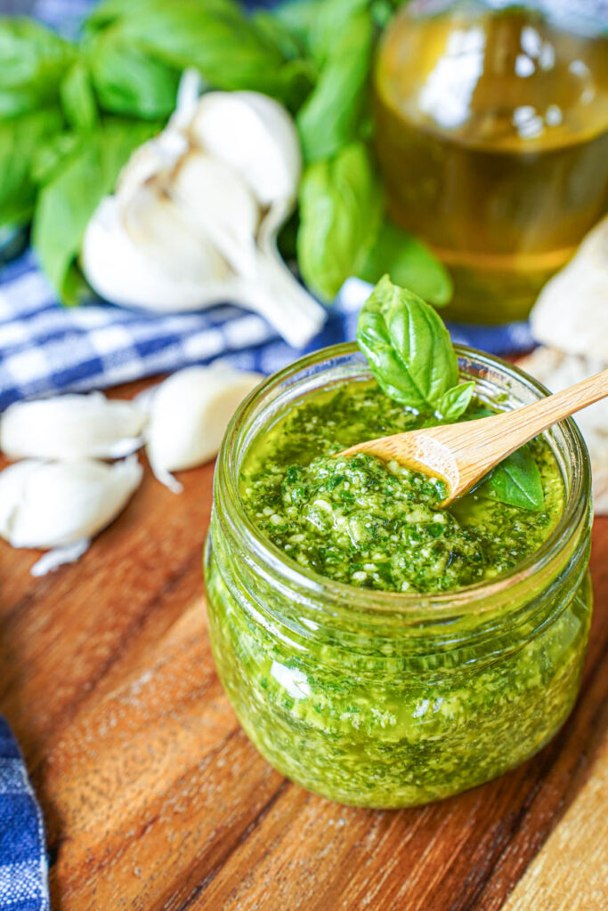 A spoon scooping Pistou (Provençal Basil Sauce) from a jar.