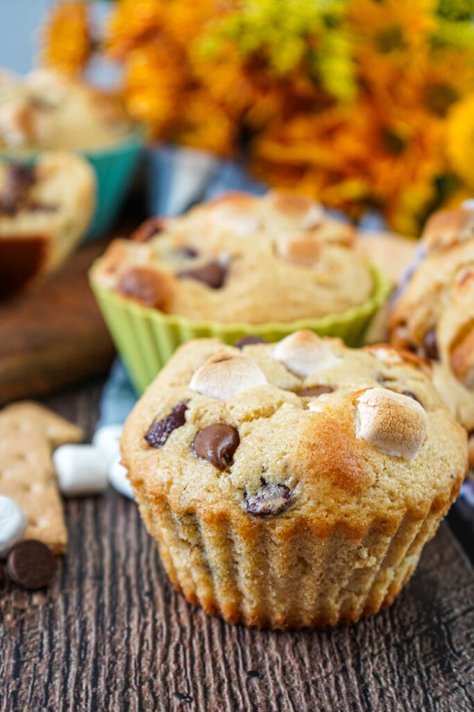 Side view of S'mores Muffins with yellow and orange flowers in the background.
