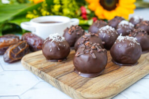 Chocolate Date Bites on a wooden board with sunflowers in the background.