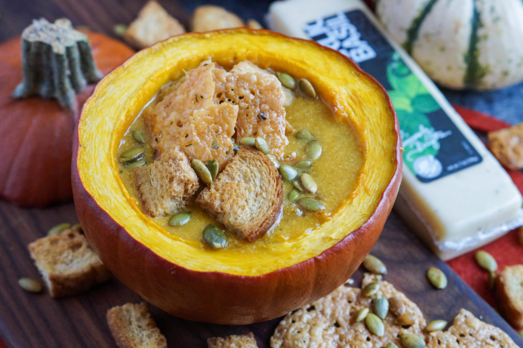 Pumpkin Cheese Soup with Garlic Basil Cheese Crisps served in a roasted pumpkin.