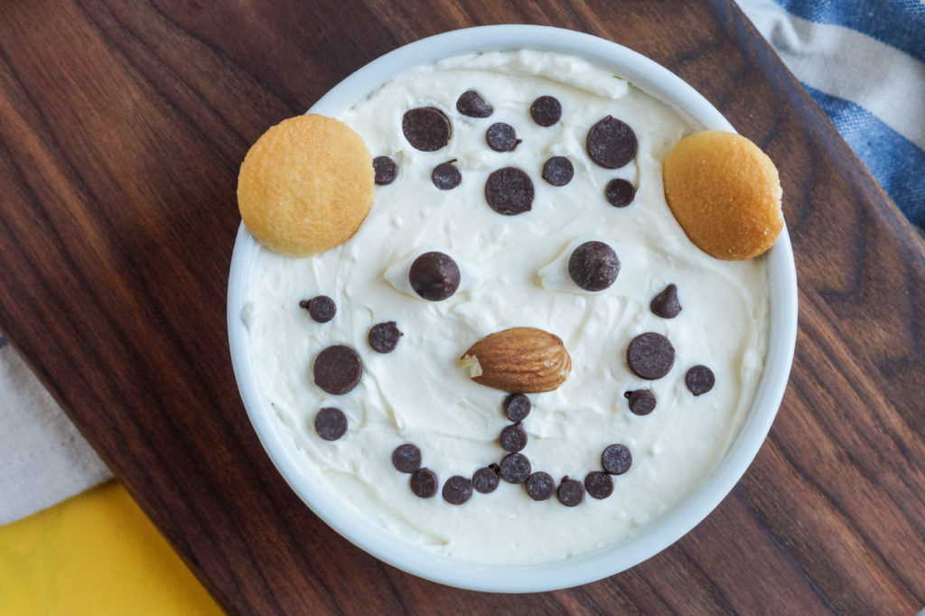 Cheetah Cheesecake with chocolate chips and Nilla wafer ears in a white ramekin on a wooden board.