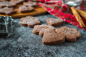 Basler Brunsli (Swiss Chocolate Spice Cookies) next to metal cookie cutters and cinnamon sticks.