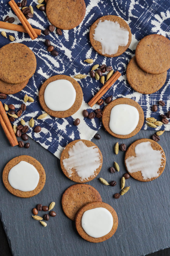 Aerial view of Coffee-Cardamom Cookies next to cardamom, coffee beans, and cinnamon sticks.