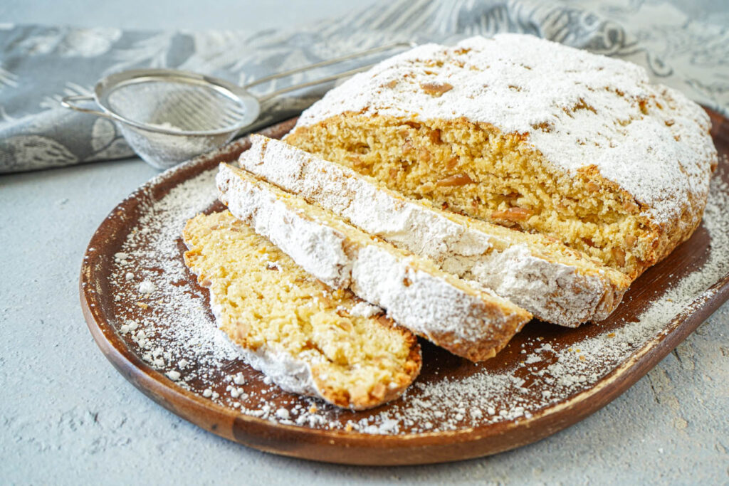 Quarkstollen (Quark-Almond Sweet Bread) on a wooden board with three slices.