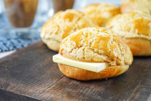 Bolo Bao (Hong Kong Pineapple Buns) on a wooden board with a slice of butter in the center.