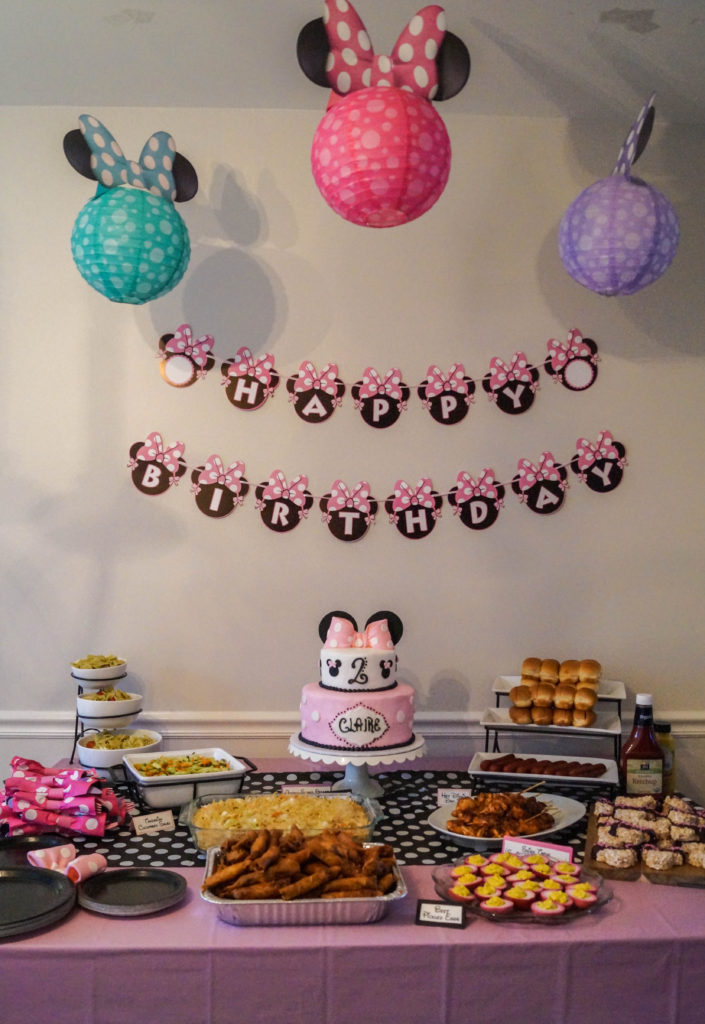 Minnie Mouse Lanterns hanging over a pink table with food and cake.
