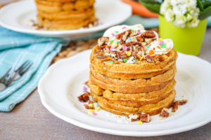 A stack of four Carrot Cake Waffles on a white plate.