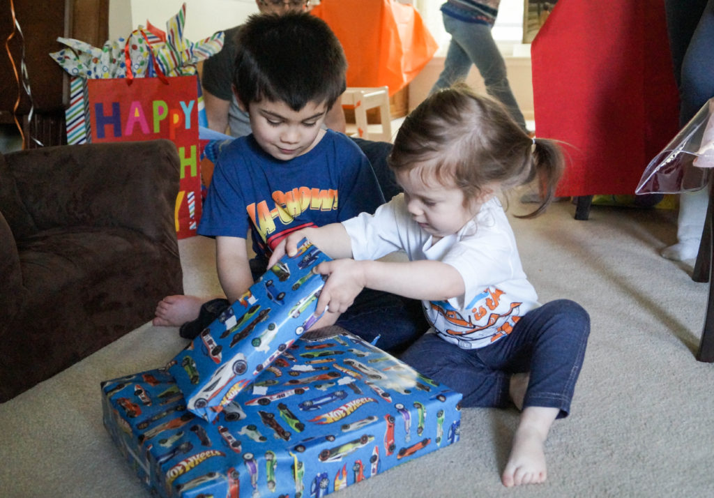 Brother and sister sitting together with two presents.