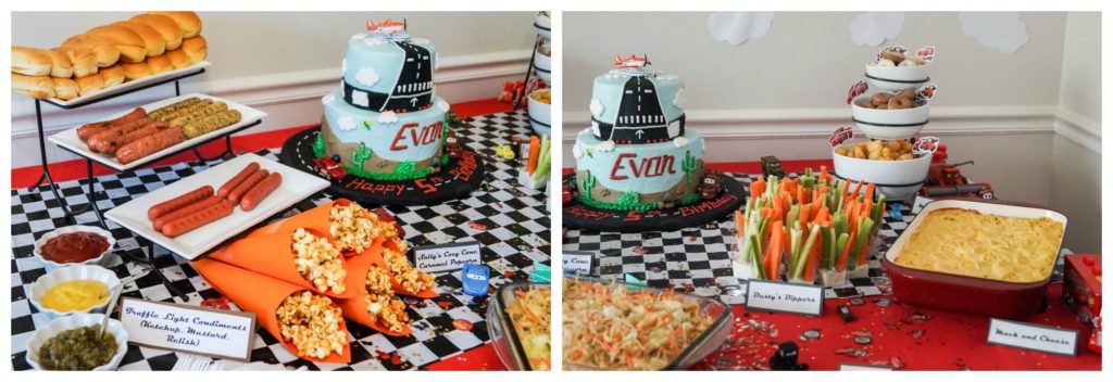 Spread of food on a red and black/white checkerboard table with hotdogs, popcorn, vegetables, and a cake.