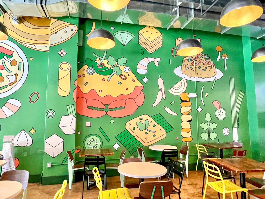 Green wall with drawings of food- crab, fried rice, tofu, lime, garlic, peppers and shrimp.