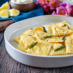 Ravioli Ricotta e Limone (Lemon Ricotta Ravioli) on a plate with melted butter and sage leaves.