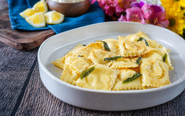 Ravioli Ricotta e Limone (Lemon Ricotta Ravioli) on a plate with melted butter and sage leaves.