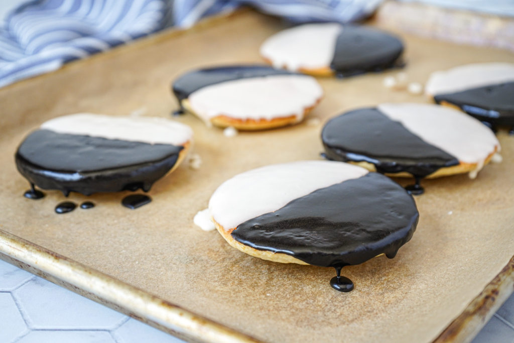 Side view of Black and White Cookies on a parchment-lined baking sheet.