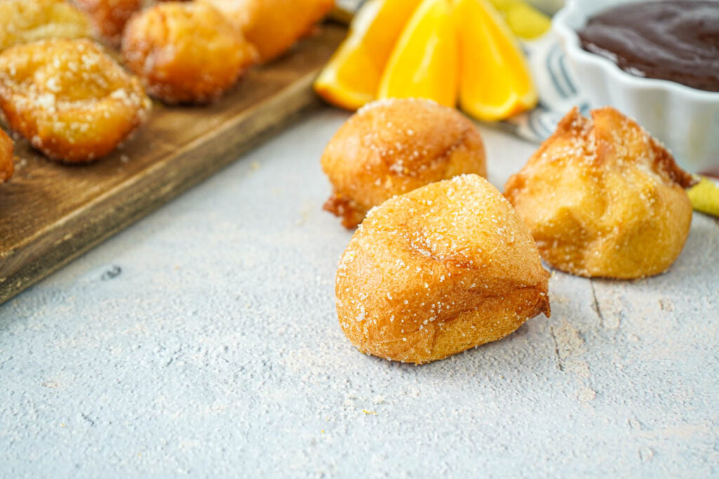 Buñuelos with Brown Velvet Glaze with orange slices in the background.
