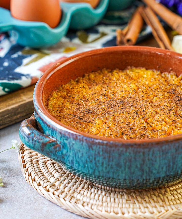 Encharcada (Portuguese Soaked Eggs) in a bowl next to lemon slices and cinnamon sticks.