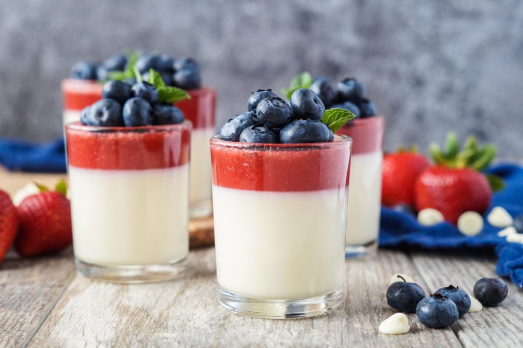 Strawberry and White Chocolate Panna Cotta in clear glasses topped with fresh blueberries.