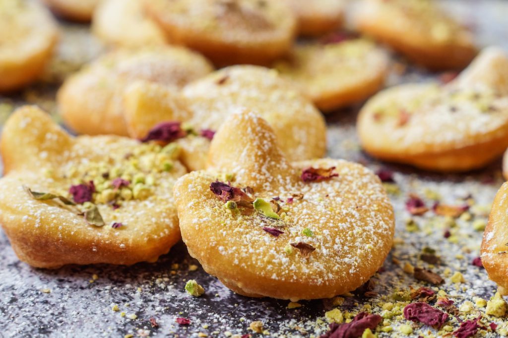 Close up of Afghani Gosh-e-Fil (Elephant Ear-Shaped Fried Pastry) topped with rose petals and crushed pistachios.