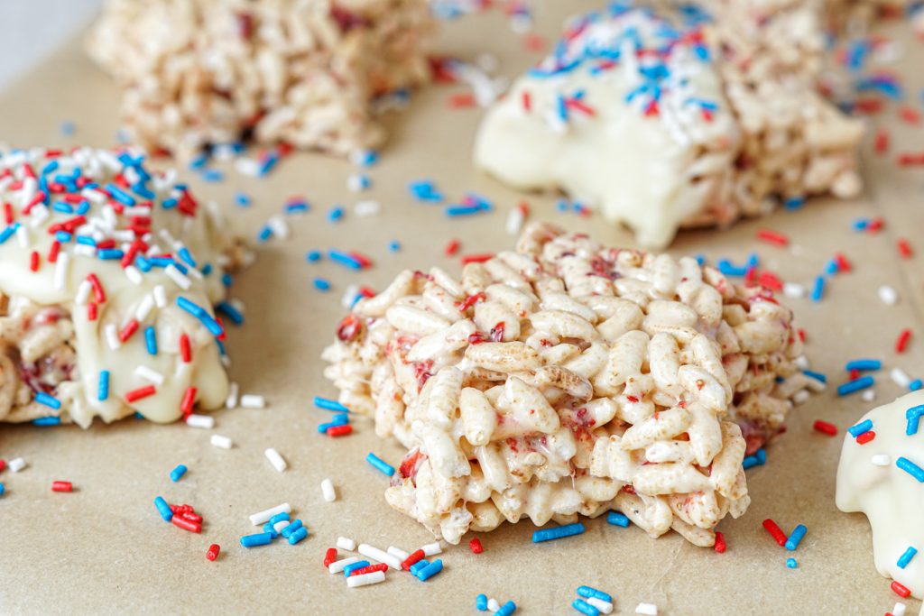 Berry Rice Krispies Treats cut into stars, dipped in white chocolate, and covered in sprinkles.