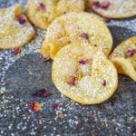 Gosh-e-Fil (Elephant Ear Pastries) on a dark surface with a dusting of powdered sugar, pistachios, and rose petals.