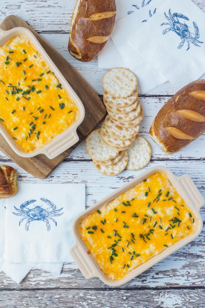 Maryland Crab Dip Aerial view of Maryland Crab Dip in two rectangular dishes alongside crackers and pretzel bread.