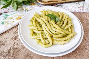 Trofie with pesto sauce on two white plates.