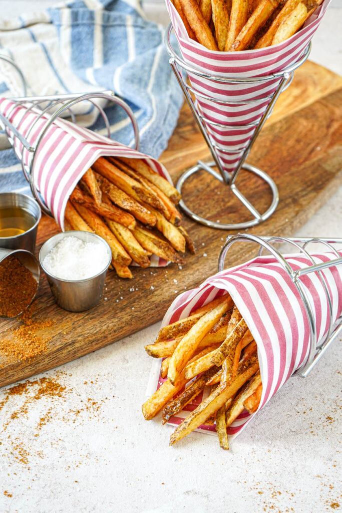 Boardwalk Fries in three cones with red and white-striped paper.