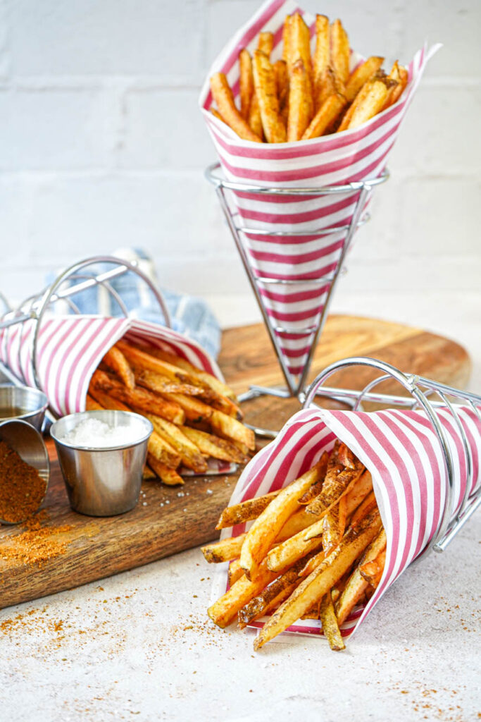 Side view of Boardwalk Fries in three cones, one standing up and two lying on their sides.