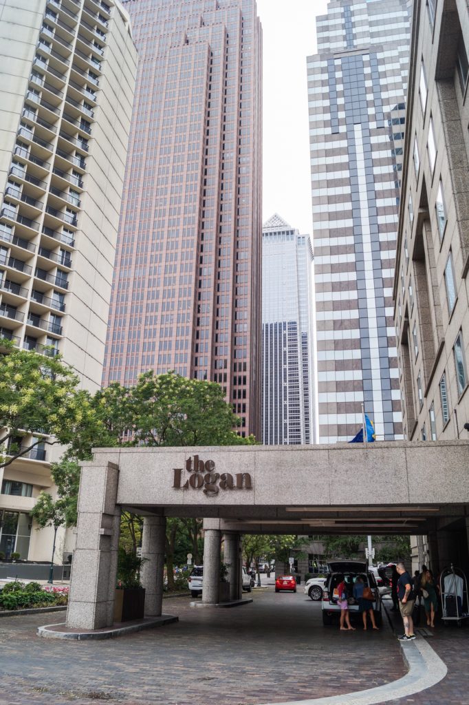 Outdoor entrance to The Logan Hotel with tall buildings in the background.