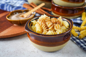 Milchnudeln (German Milk Noodles) in a brown bowl with cinnamon sugar in the background.