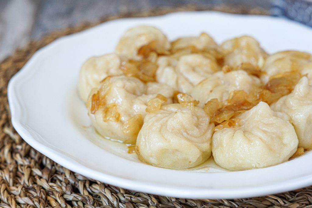 Kartopilis Khinkali (Small Potato Khinkali Dumplings) with caramelized onions on a white plate.
