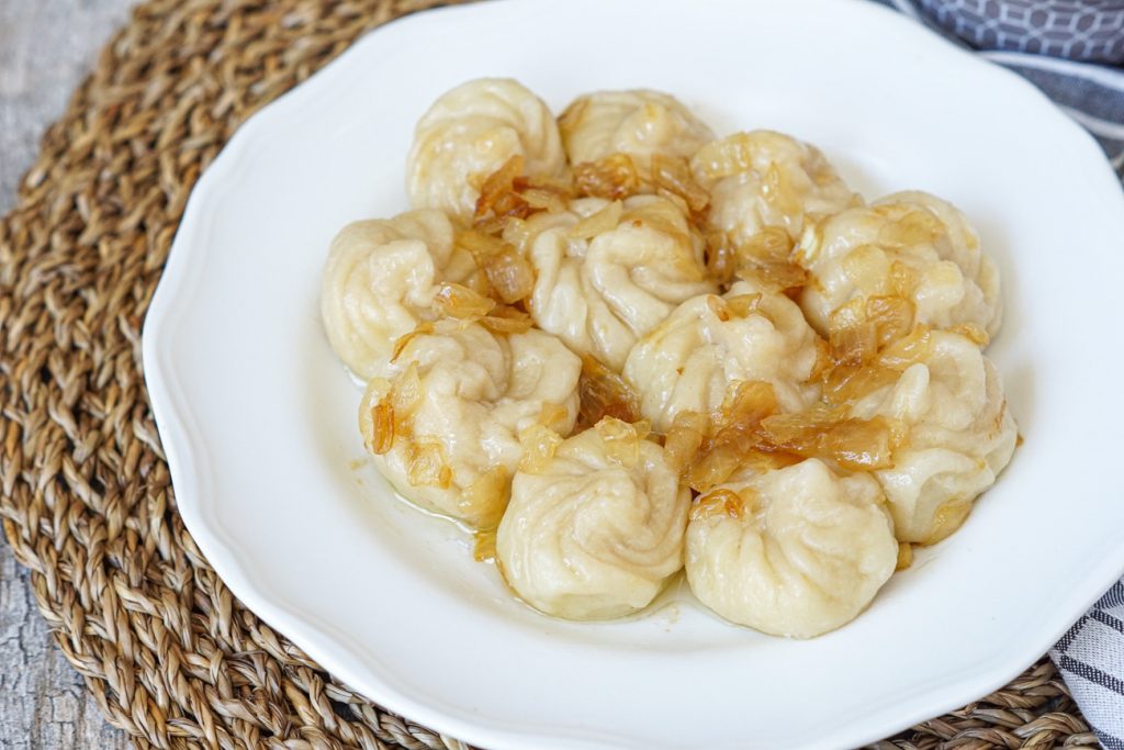 Kartopilis Khinkali (Small Potato Khinkali Dumplings) on a plate with caramelized onions.