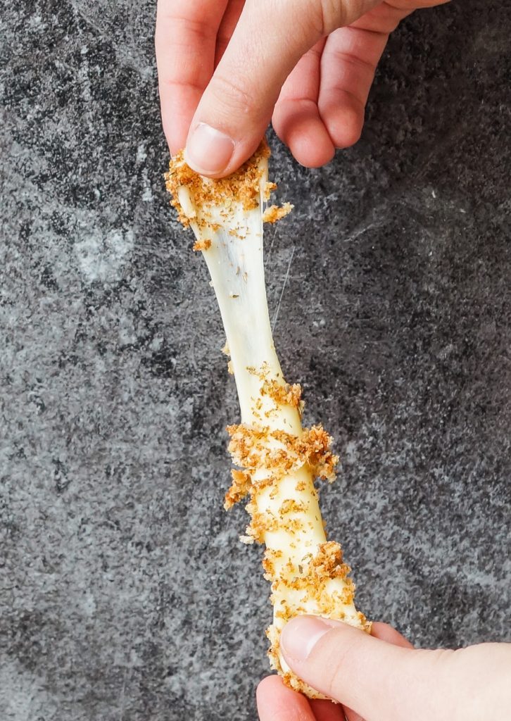 Pulling a mozzarella stick to show the stretchy cheese.