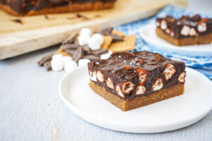 Two slices of S'mores Bars on two white plates.