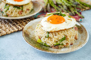 Asparagus Fried Rice on a brown plate and topped with a fried egg.
