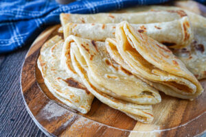 Folded Chapati Za Ngozi (Kenyan Soft Layered Flatbread) on a wooden board.