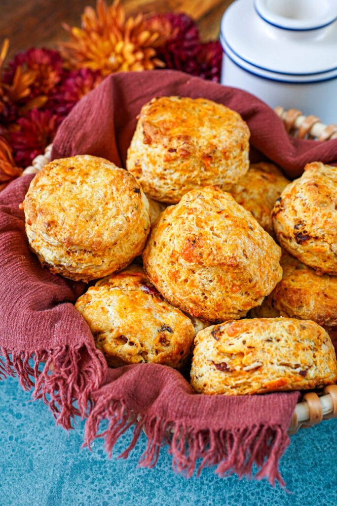 A towel lined basket filled with Cheddar Sun-Dried Tomato Biscuits.
