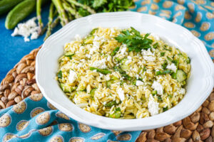 Lemon Orzo Pasta Salad in a white bowl with a parsley sprig.
