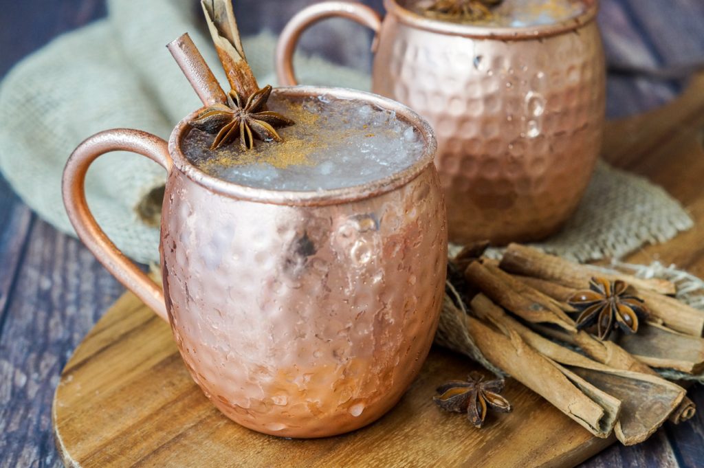 El Fusilado cocktail in two copper mule glasses with cinnamon sticks and star anise.