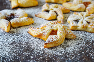 Joulutorttu (Finnish Christmas Tarts) on a dark surface with a dusting of powdered sugar.