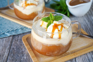 Salted Caramel Affogato in two glass cups with caramel sauce and mint.
