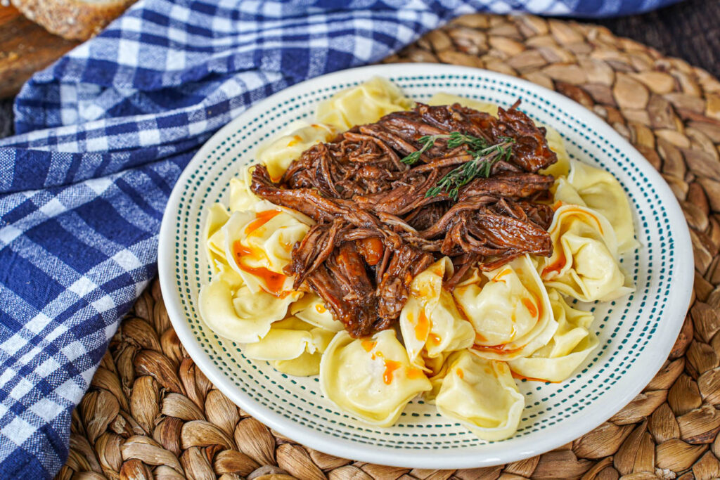Shredded Beef Chuck Roast on a plate with tortellini.