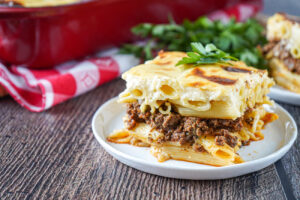 A slice of Macarona Bechamel (Egyptian Baked Pasta) on a white plate.