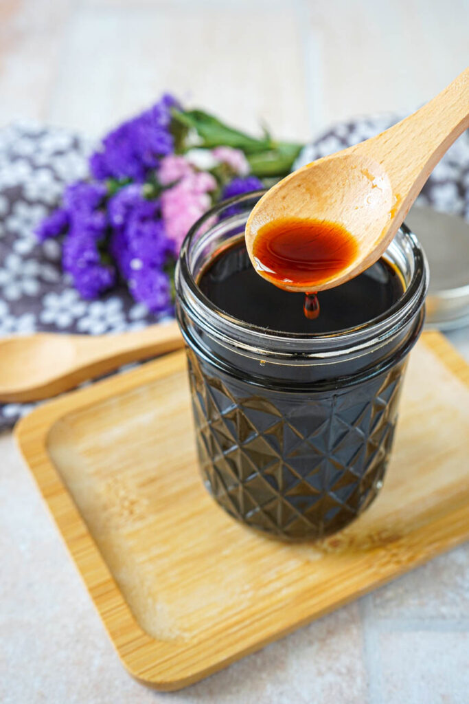 A spoonful of Homemade Teriyaki Sauce dripping into a glass jar.