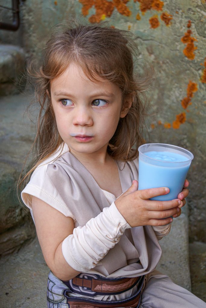 Girl holding cup of blue milk.