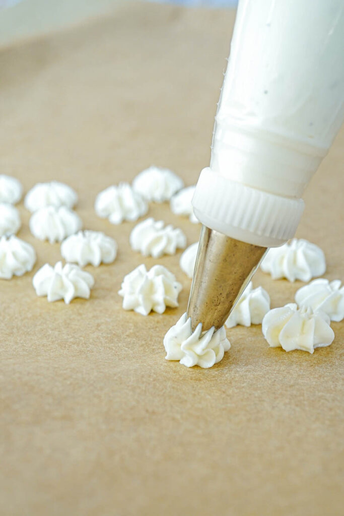 Piping Vanilla Bean Frozen Yogurt Drops onto a piece of parchment.