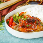 Baked Teriyaki Chicken on a plate with roasted vegetables and rice.