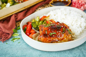 Baked Teriyaki Chicken on a plate with roasted vegetables and rice.
