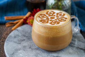Maple Cinnamon Latte in a glass with cinnamon-dusted flower design on top.